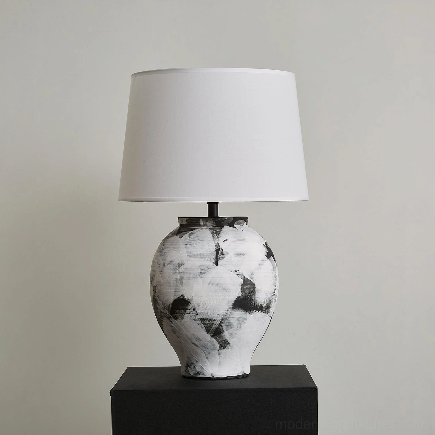 Modern Malta table lamp featuring urn-shaped hand-painted ceramic base displayed on black pedestal unlit