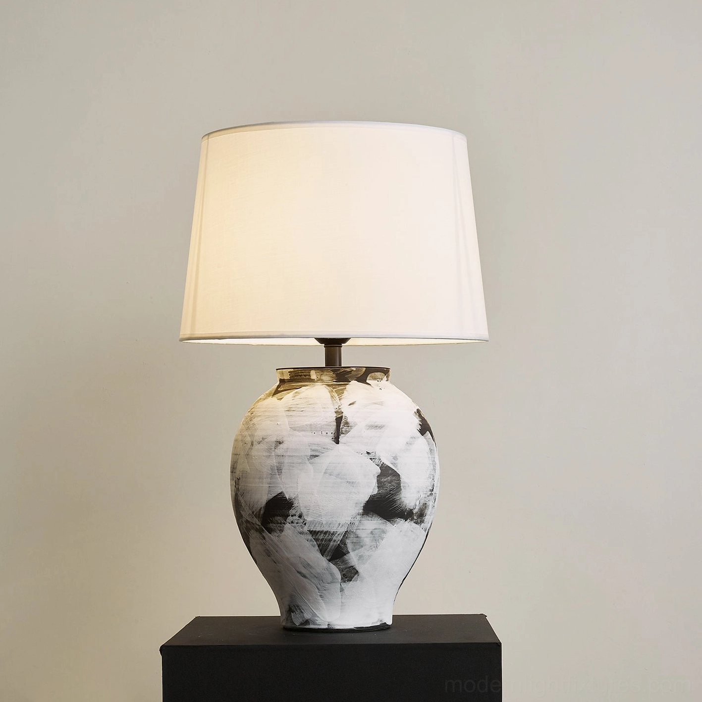 Lit Malta ceramic table lamp with abstract painted base casting warm ambiance in modern interior