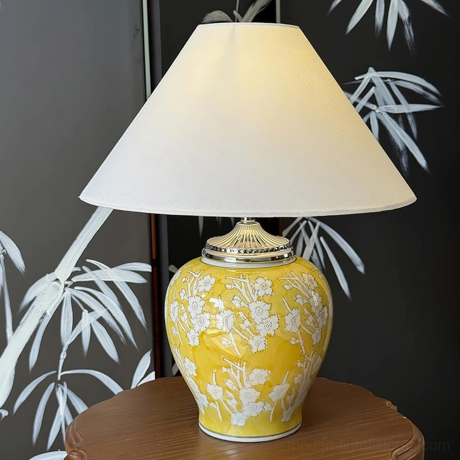 Golden yellow hand-glazed ceramic table lamp with white floral medallions and tapered linen shade, warm ambient lighting piece for eclectic and bohemian interiors