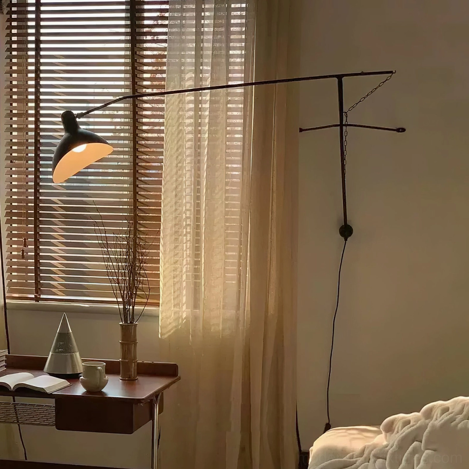 Matte black swing arm wall lamp in bedroom with wooden window blinds