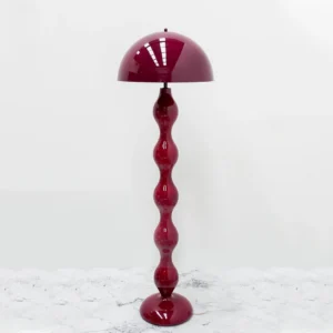 Modern gourd-shaped floor lamp with glossy burgundy finish displayed in three-quarter view on white marble tabletop, contemporary interior styling