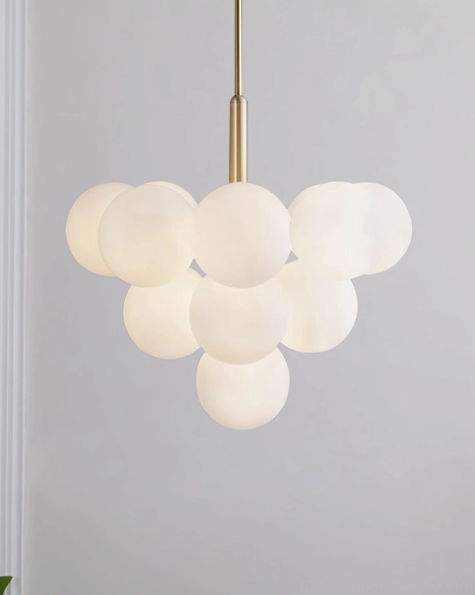 Brass and frosted glass chandelier side profile view on gray background showing design details