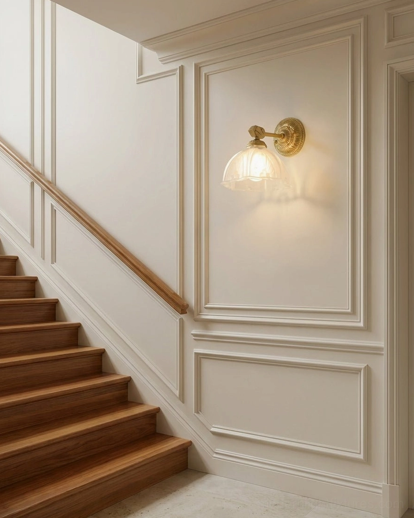 Marceau brass wall sconce installed on stairwell with wainscoting, serving as compact accent lighting for staircase design