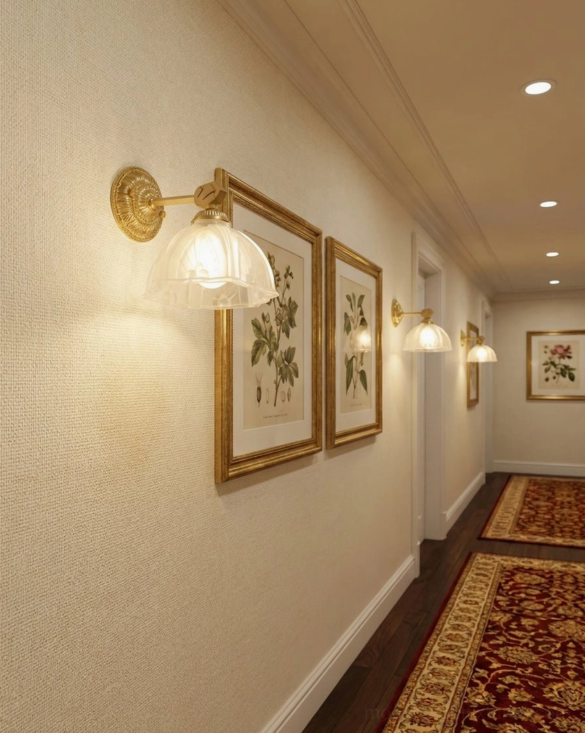 Multiple Marceau brass wall sconces illuminating residential hallway corridor with patterned area rugs and gallery-style placement