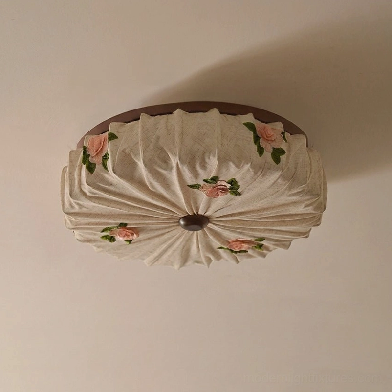 Close-up detail of Maribelle flush mount showing radial pleated linen fabric and molded rose flowers with dark painted alloy rim