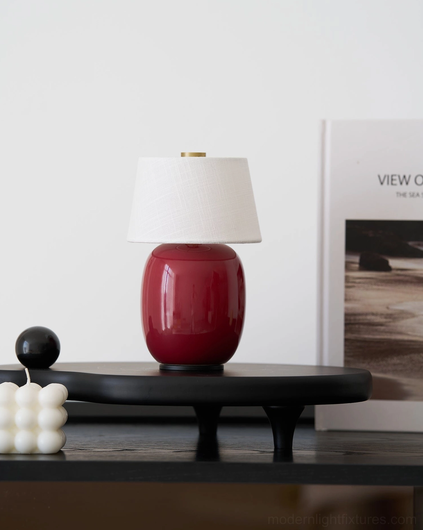 Compact wine-red ceramic table lamp displayed on black decorative tray with minimalist Nordic styling