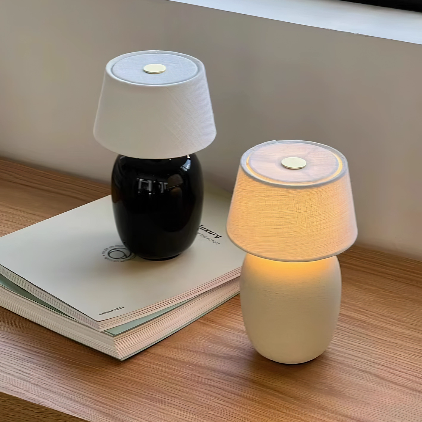 Pair of black and sand ceramic table lamps on wooden desk with stacked books – minimalist workspace lighting
