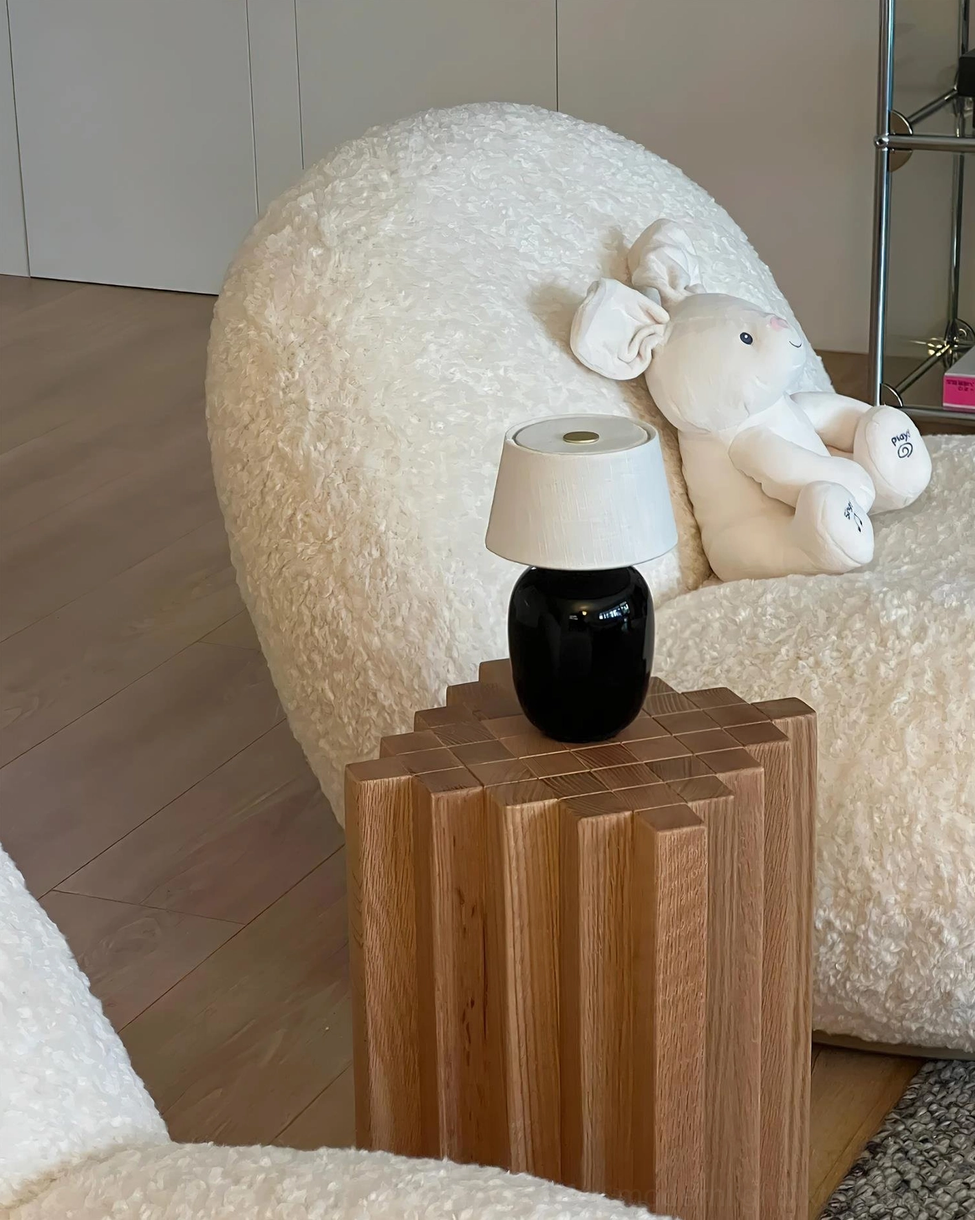 Matte black ceramic table lamp on side table next to boucle armchair – contemporary living room ambiance