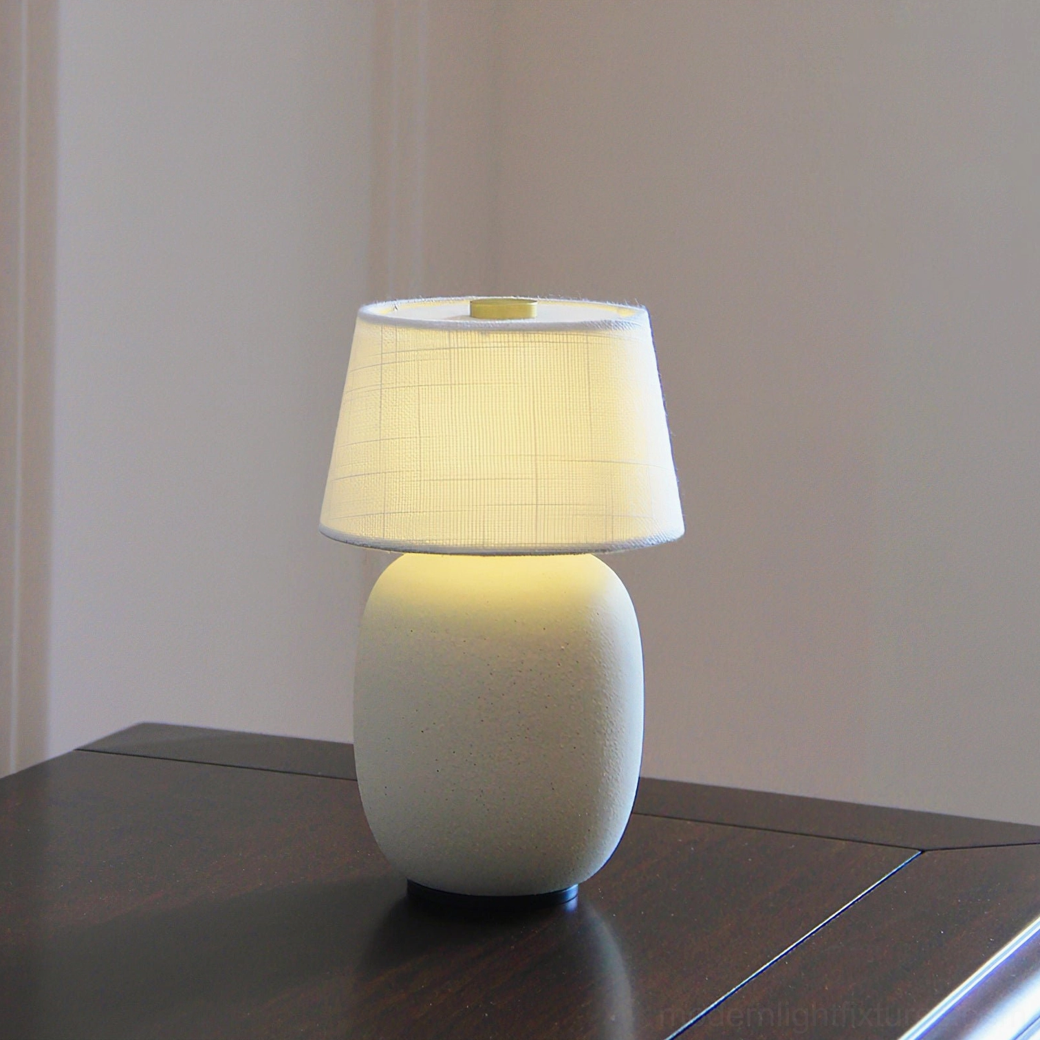 Off-white textured ceramic table lamp with linen fabric shade on dark dining table – illuminated ambient light