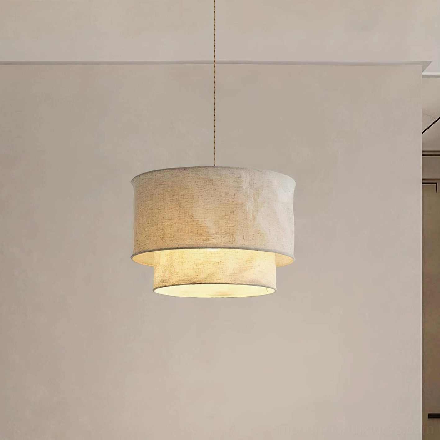 Fabric drum shade pendant lamp with warm glowing illumination and natural linen texture on neutral residential wall