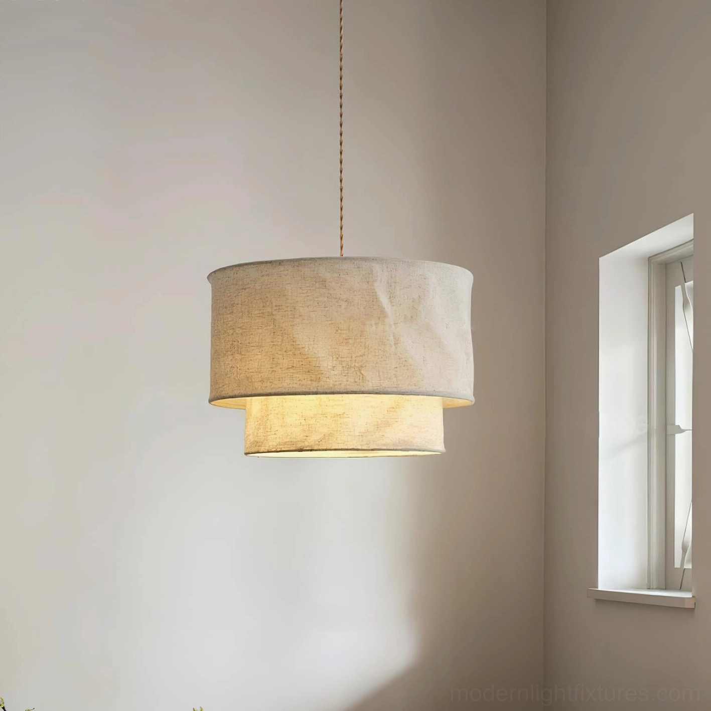 Two-tier textured linen pendant light in residential interior with warm ambient glow and minimalist wall decor