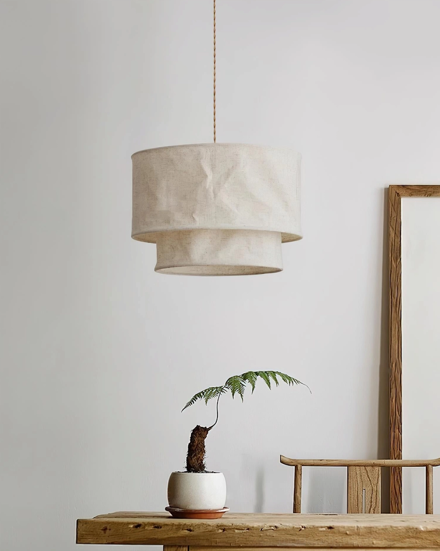 Double-layer fabric pendant light with crumpled linen shade in minimalist foyer with warm wooden home accents