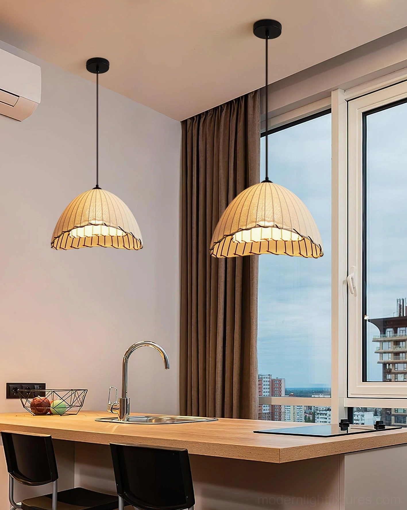 Two Maris pleated linen pendant lamps suspended above kitchen island bar with black cables