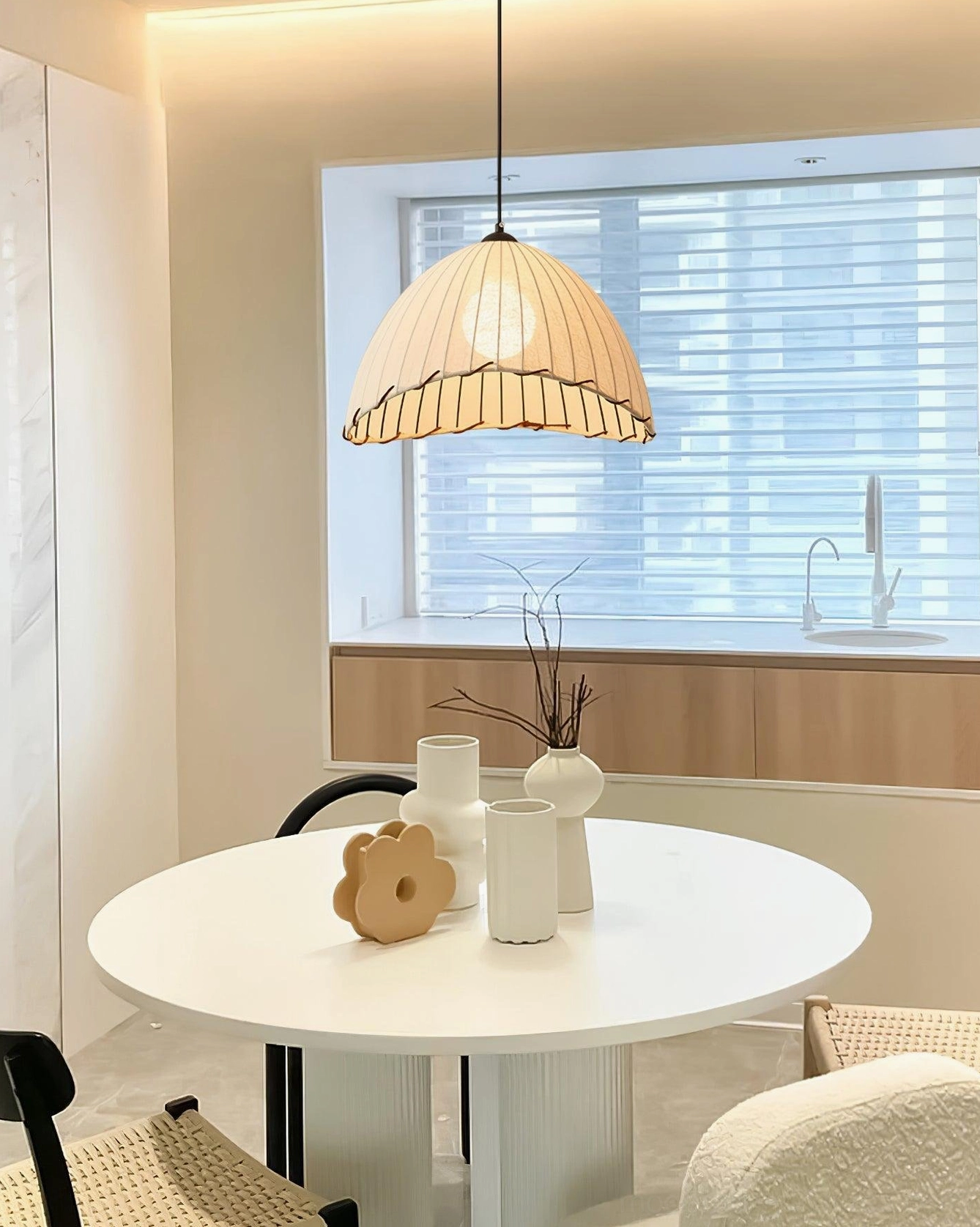 Contemporary pleated linen pendant light above kitchen dining table in bright minimalist interior