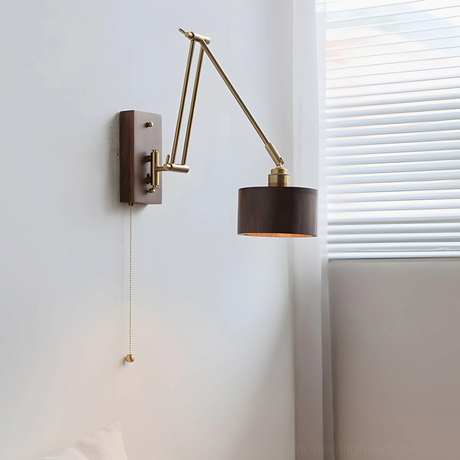 Adjustable brass wall sconce mounted on plain white wall with side profile showing articulated swing mechanism and pull chain