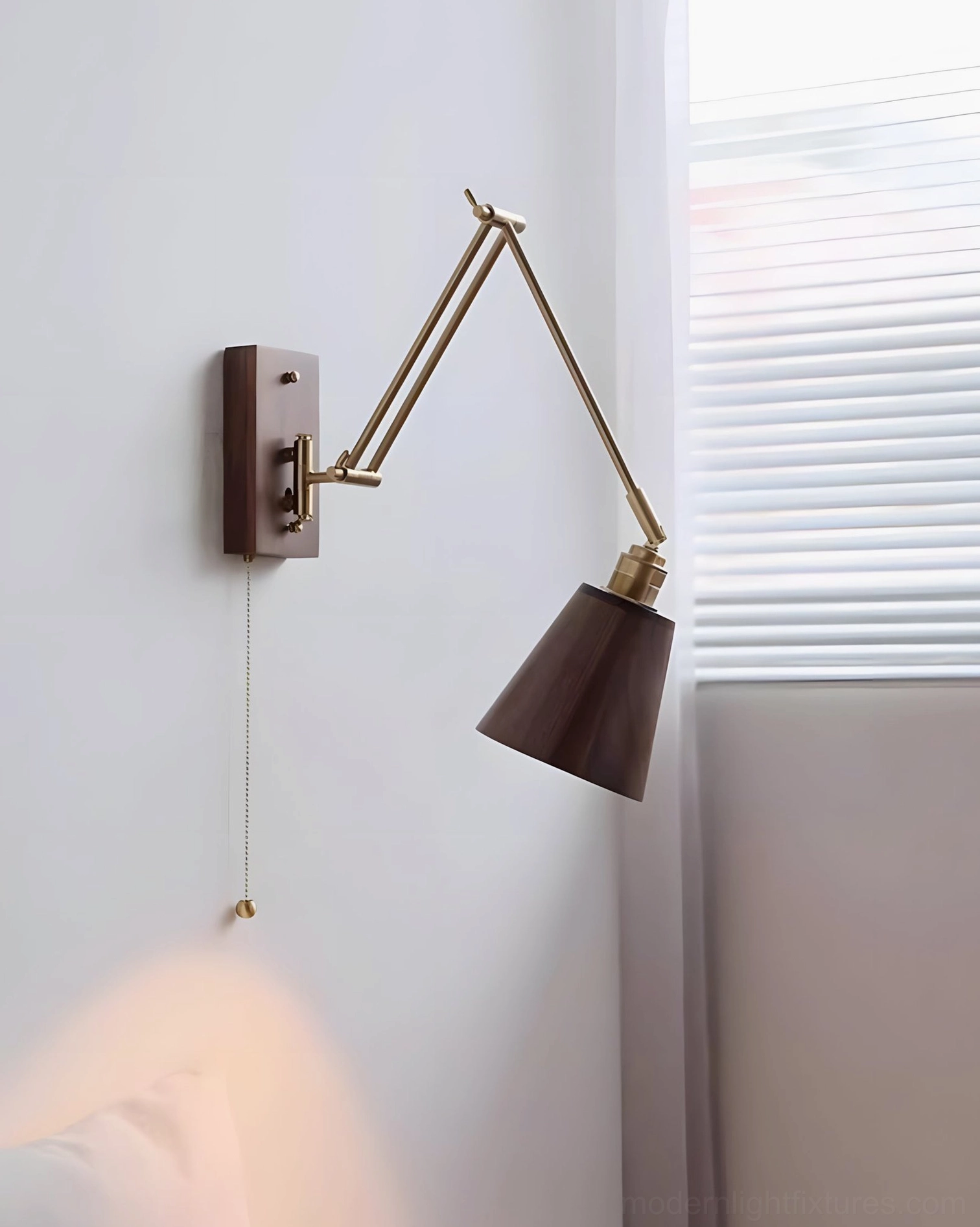 Mid-century modern swing arm wall sconce detail view highlighting brass articulation joints and warm wood finish