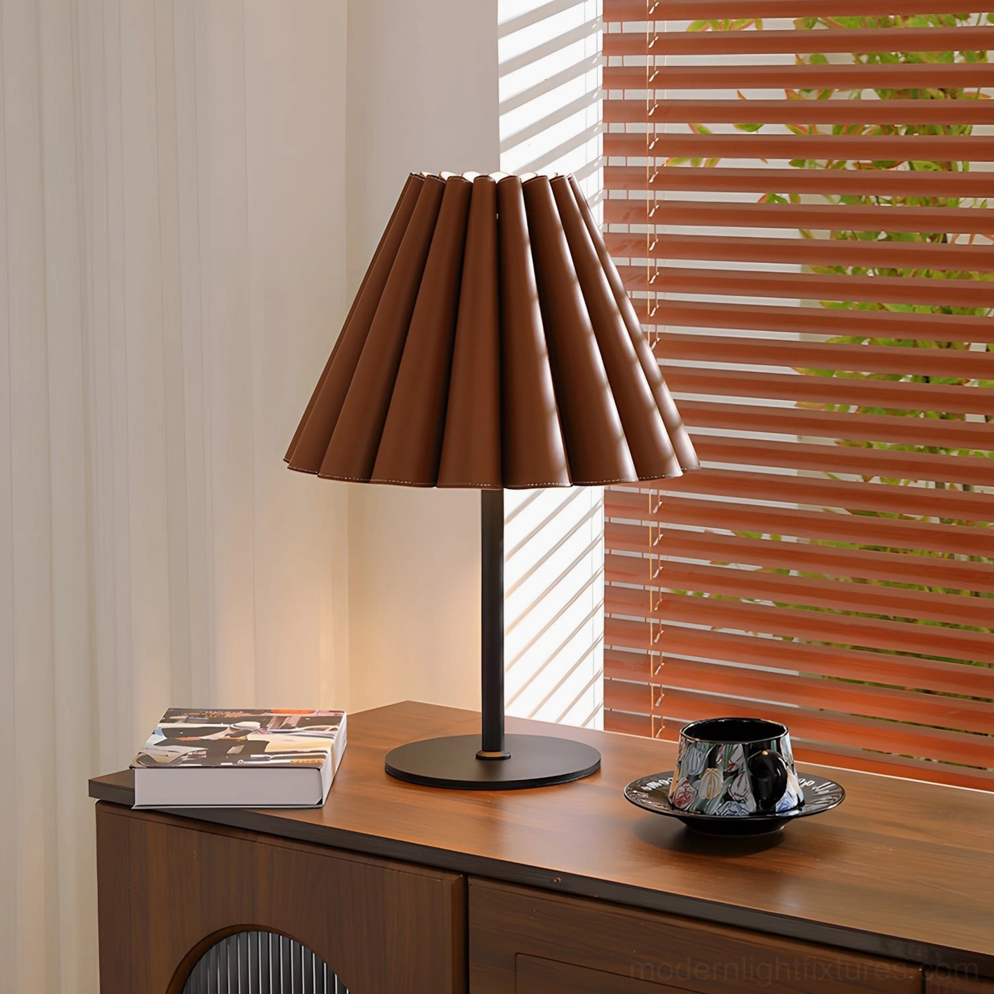 Tan leather pleated table lamp styled on wooden cabinet with coffee cup and book in warm ambient lighting
