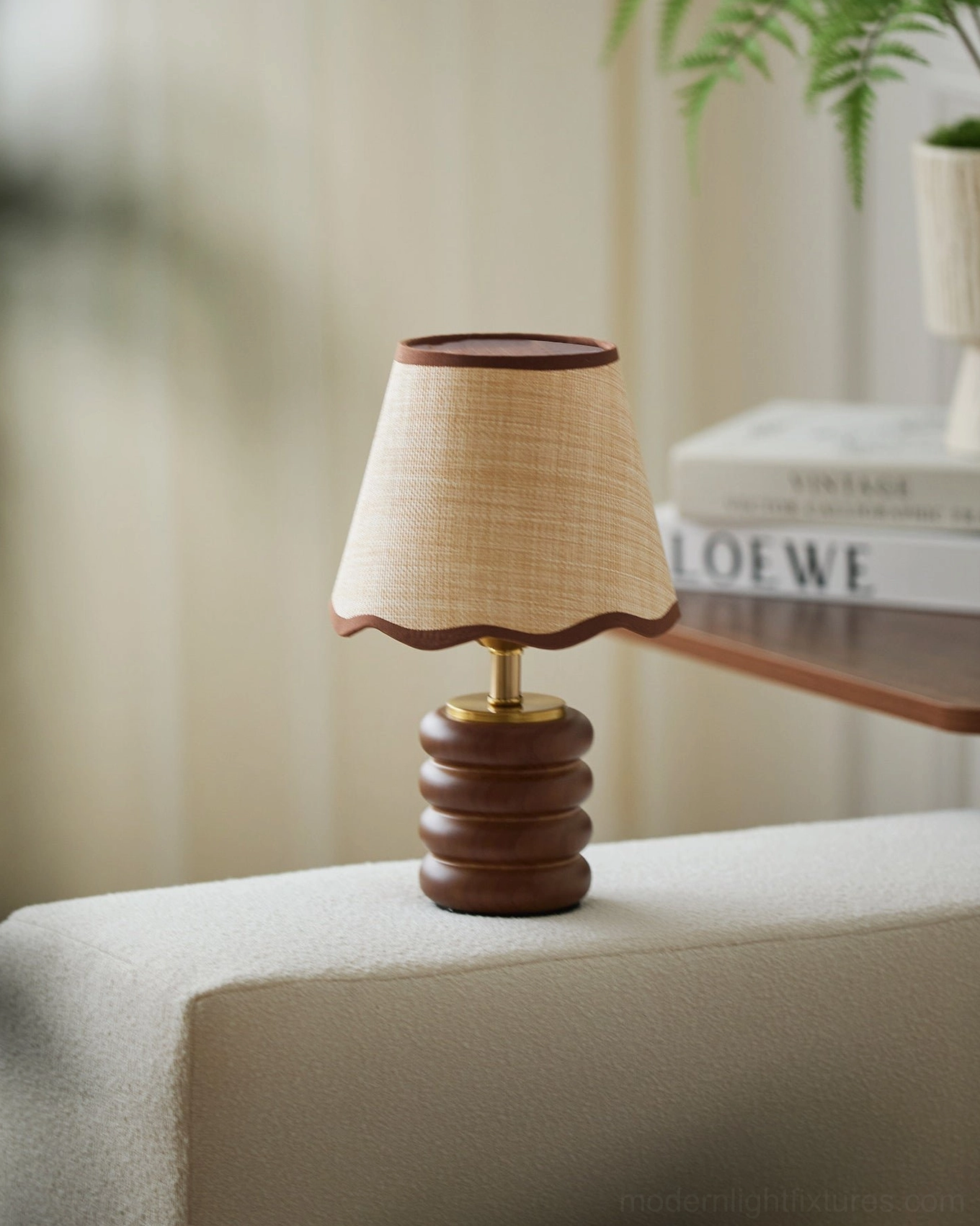 Marlowe table lamp with woven raffia shade and walnut turned base on sofa arm table, soft ambient light with blurred books