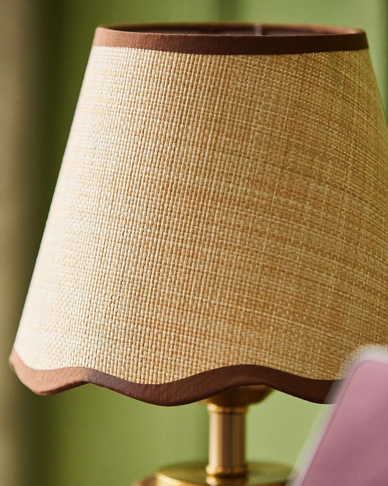Detail view of Marlowe lamp shade and base, showing woven raffia fabric with wavy brown trim and brass hardware
