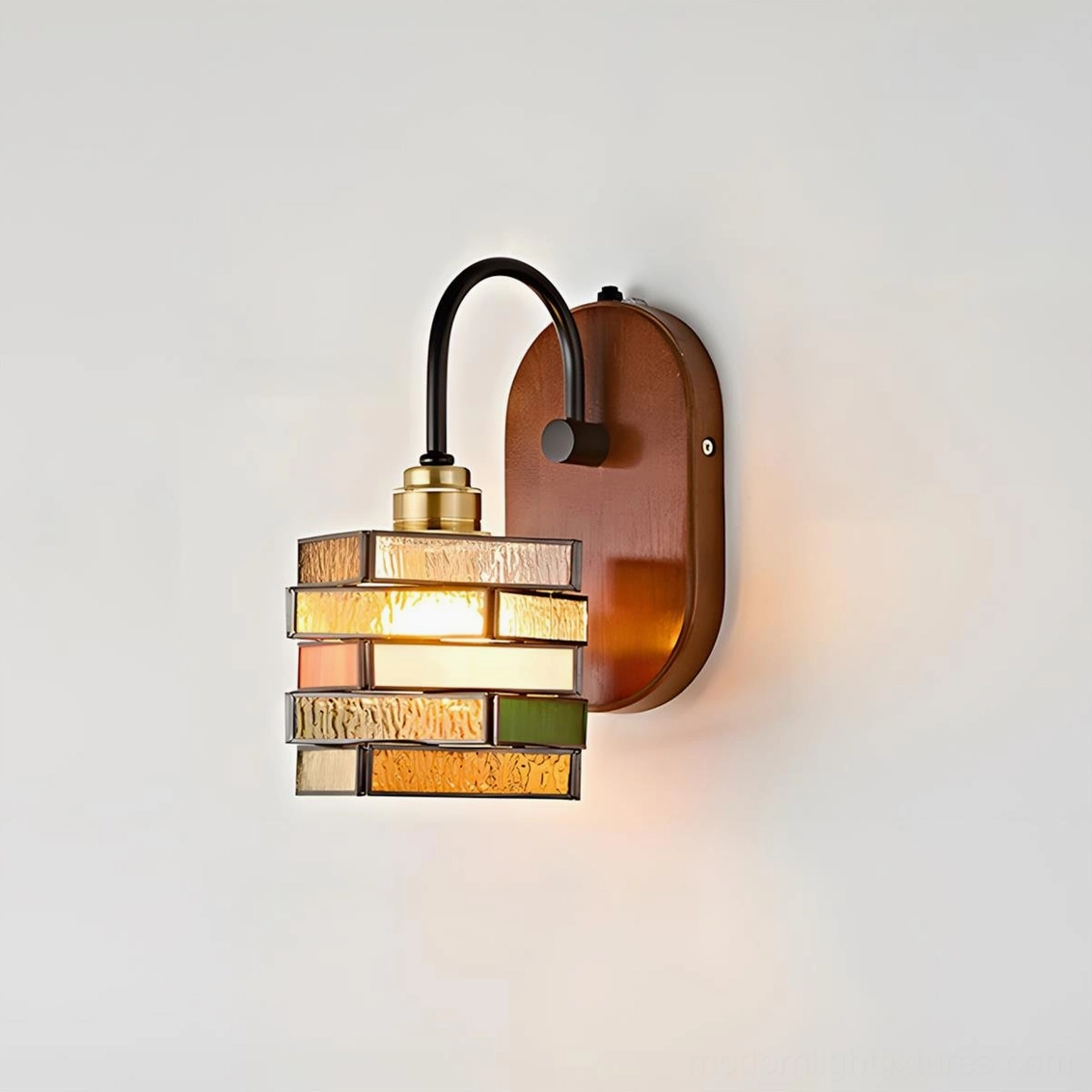 Marlowe wall sconce illuminated showing warm amber blush and green layered stained glass mosaic effect