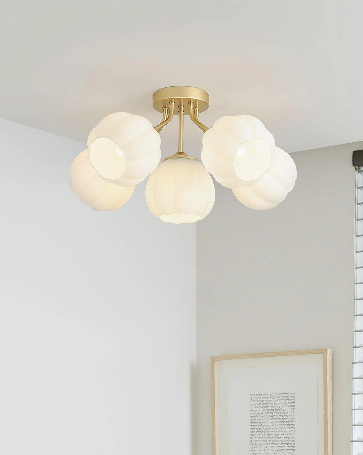 Angled view of 5-head Marra ceiling light with warm ambient lighting installed in residential room, brushed gold hardware and pumpkin glass