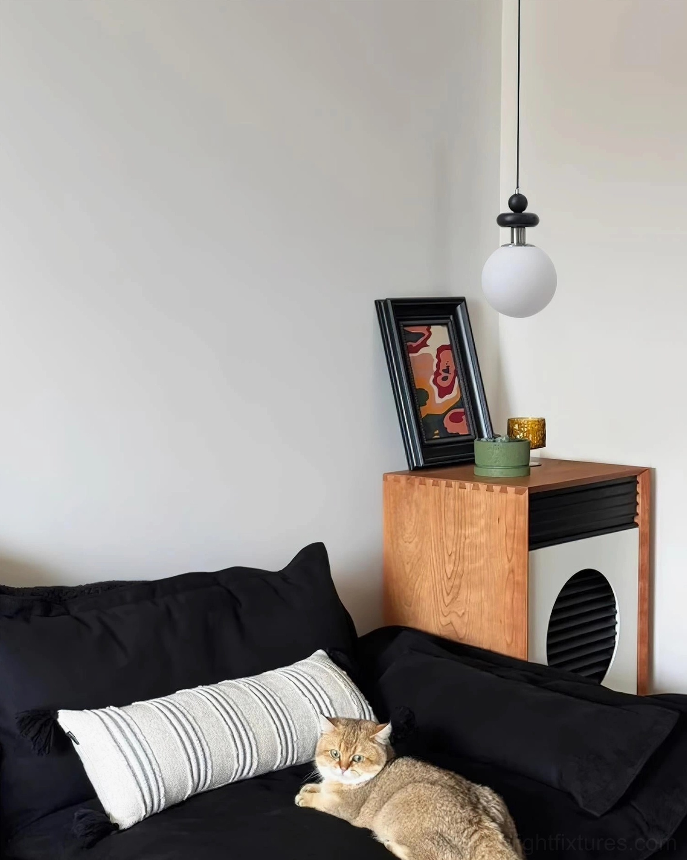 Marra Globe Pendant Light in living room sofa zone viewed from distance, matching black sofa and wooden side cabinet furniture