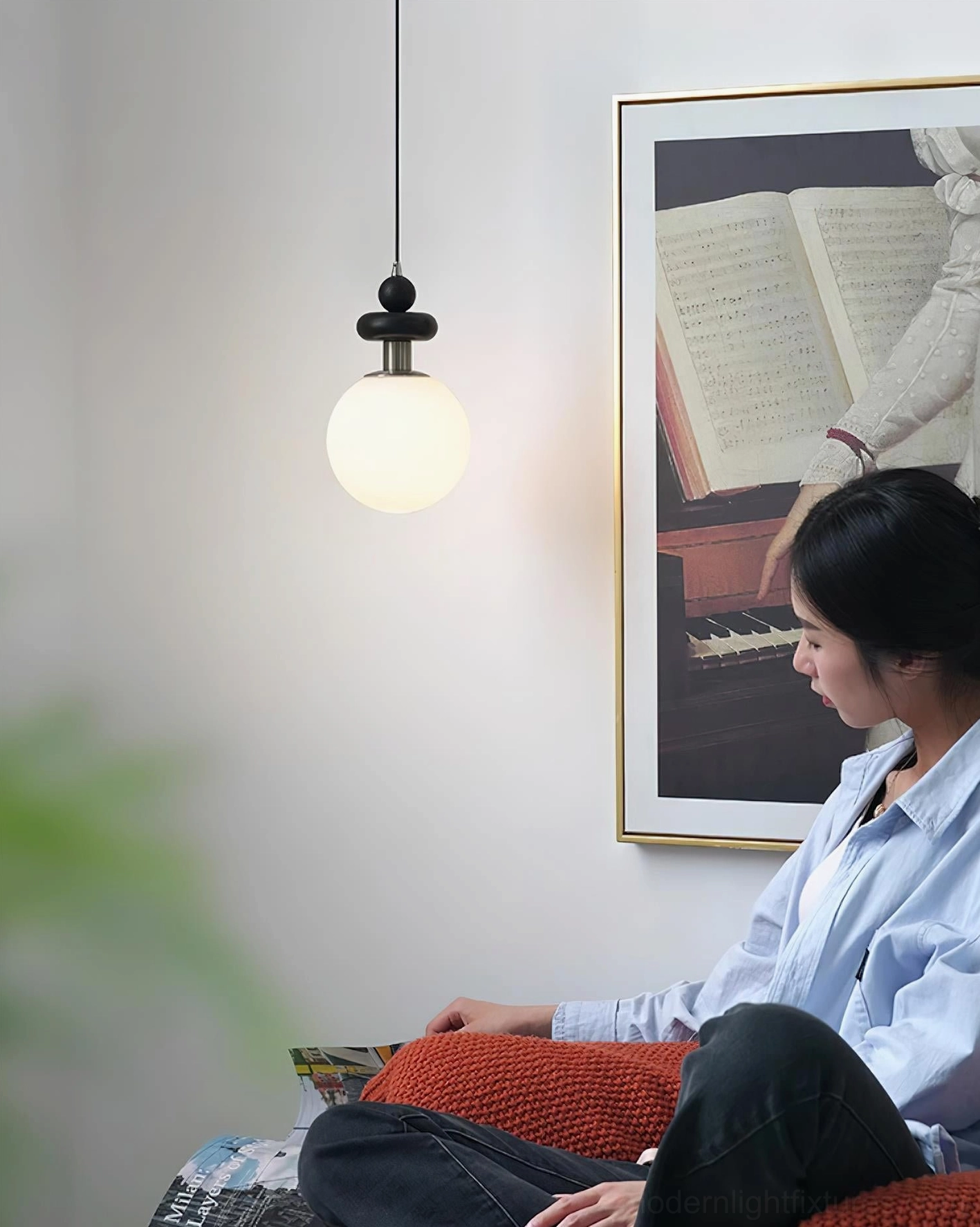 Marra Globe Pendant Light illuminating a home reading corner, suspended above seated person in intimate lighting setting