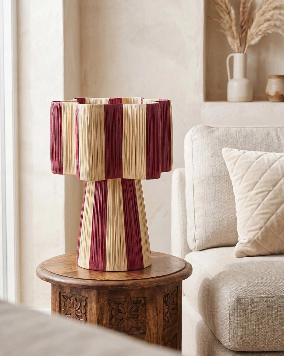 Maruvia woven cord lamp on carved wooden side table near linen sofa with decorative wall niche, living room vignette