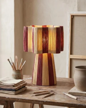 Maruvia boho table lamp on rustic wooden desk with stationery and textiles, three-quarter angle showing woven pattern detail