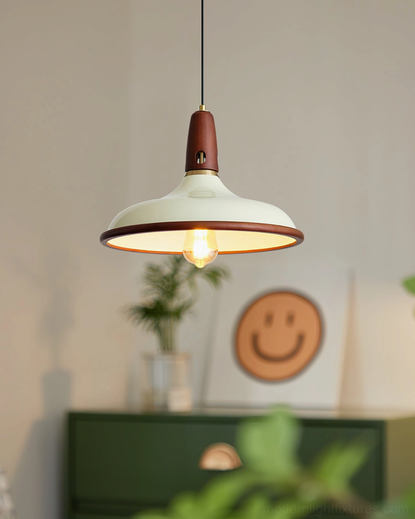 Modern pendant lamp in living room with green cabinet wall art and warm exposed bulb lighting