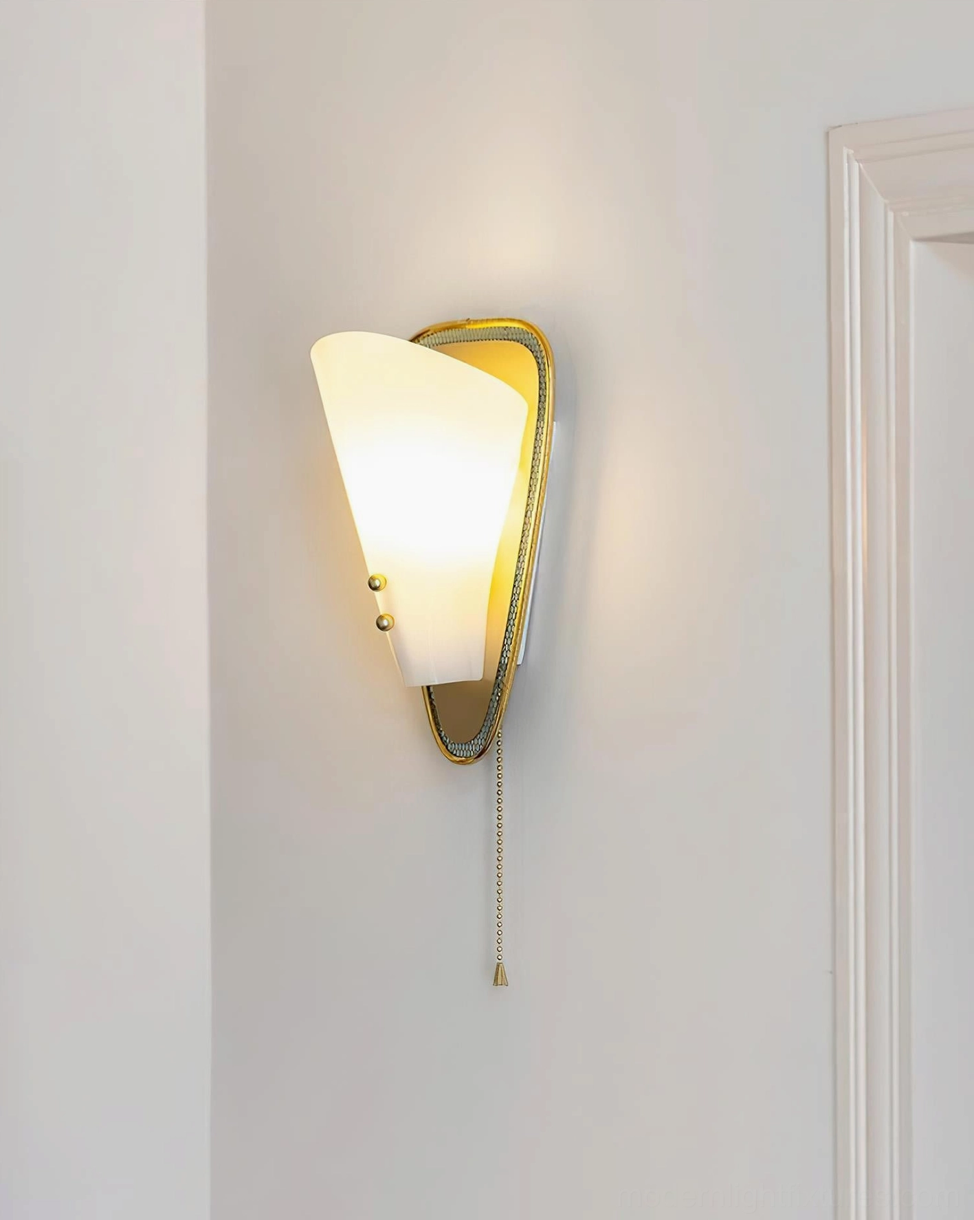 Marzio wall sconce lit creating warm ambient illumination with tapered shade and brass accents