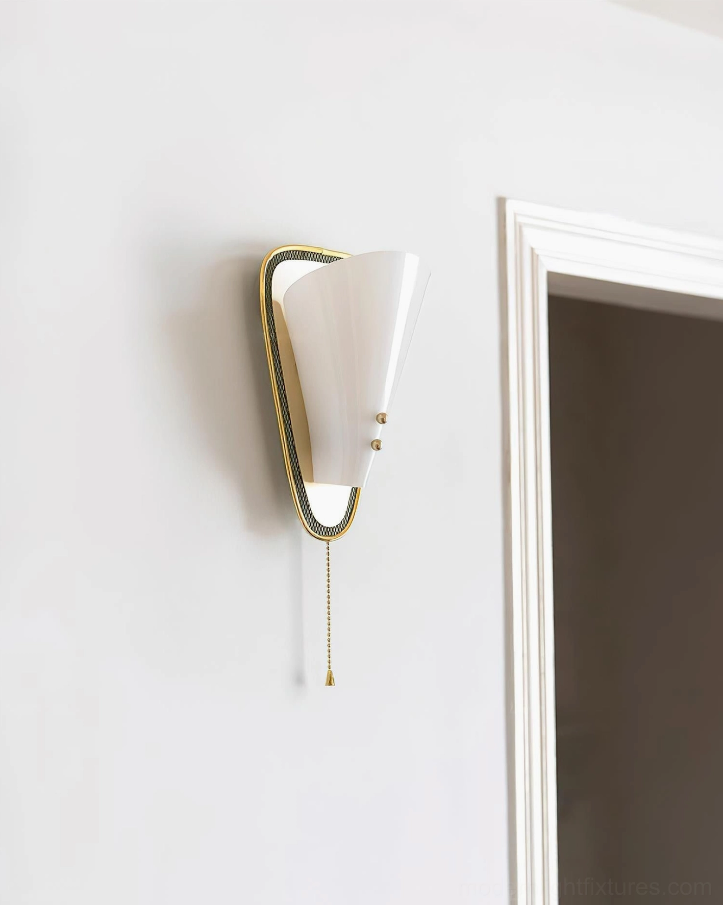 Marzio wall sconce in home entryway displaying tapered white shade and brass metal frame against doorway