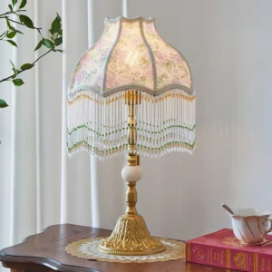 Masa vintage rose table lamp three-quarter view with pink rose patterned shade, green beaded trim, and brass base styled with decorative tea set