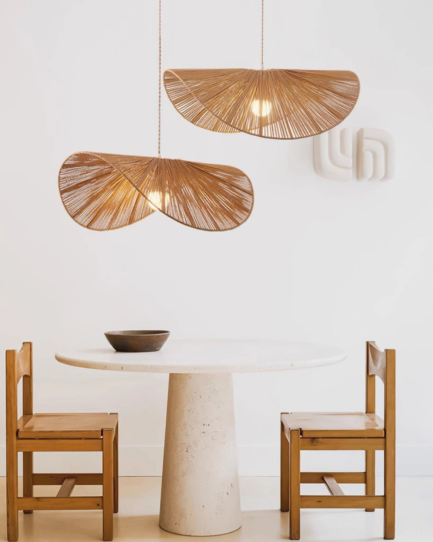 Pair of matching natural fiber woven straw hat pendant lights in boho rustic dining space