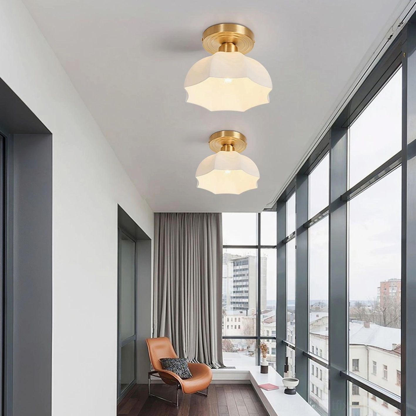 Pair of matching scalloped brass ceiling lights installed in contemporary urban apartment with floor-to-ceiling windows