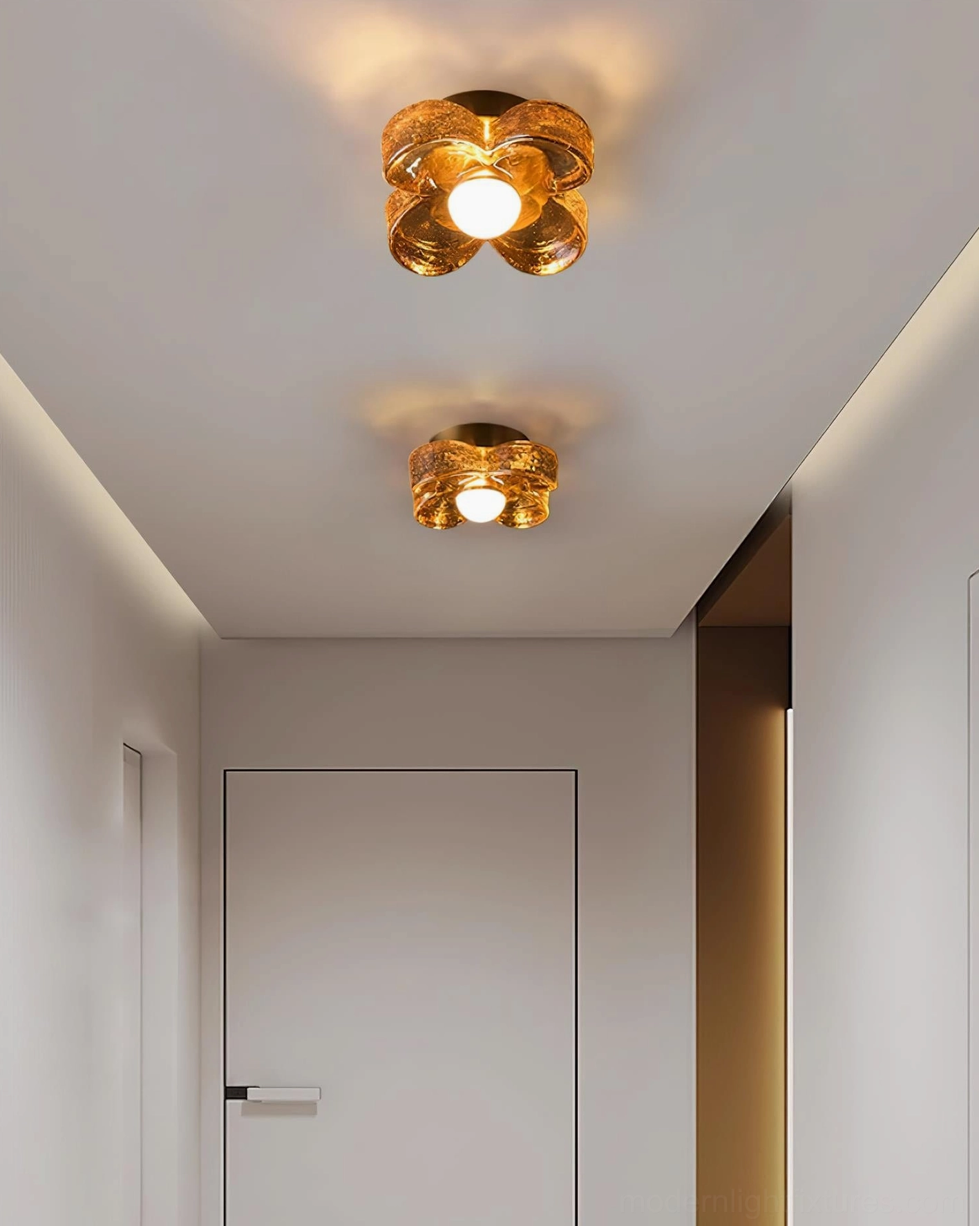 Pair of matching four-leaf clover ceiling lights with brass and amber glass installed in apartment entryway overhead