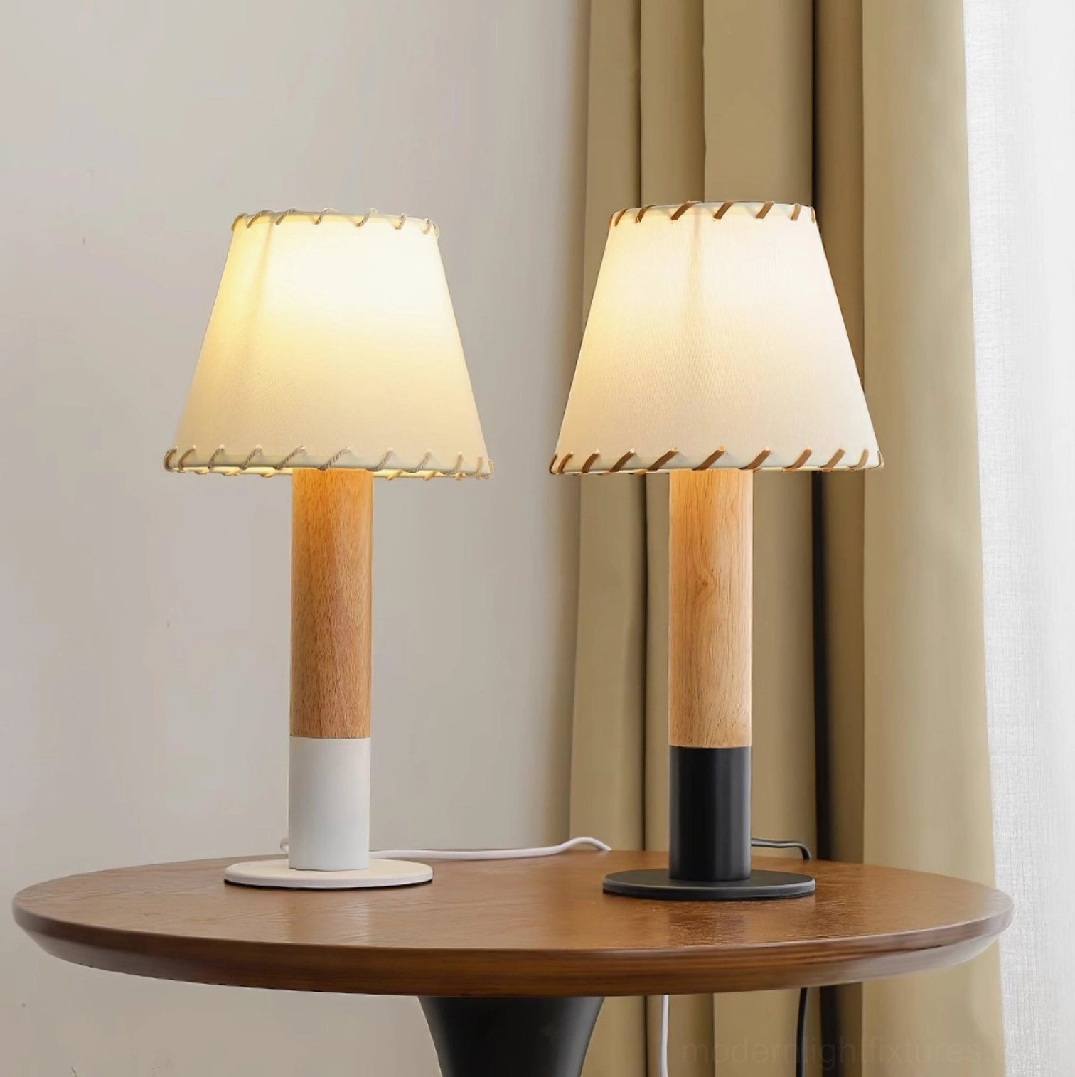 Two matching farmhouse table lamps with black and white fabric base variants on wooden side table