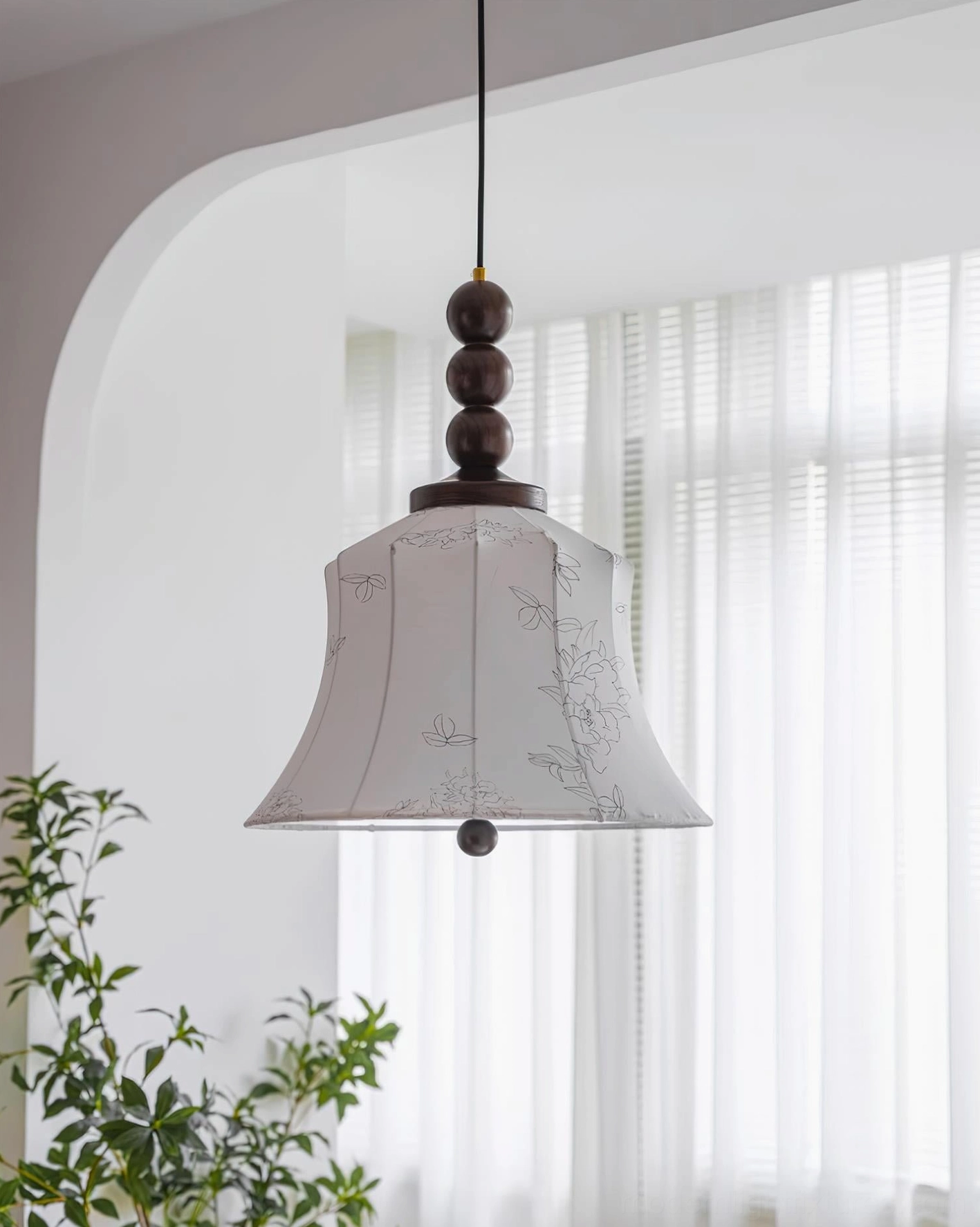 Materia hanging pendant lamp with floral printed shade in interior space with sheer curtains and plants