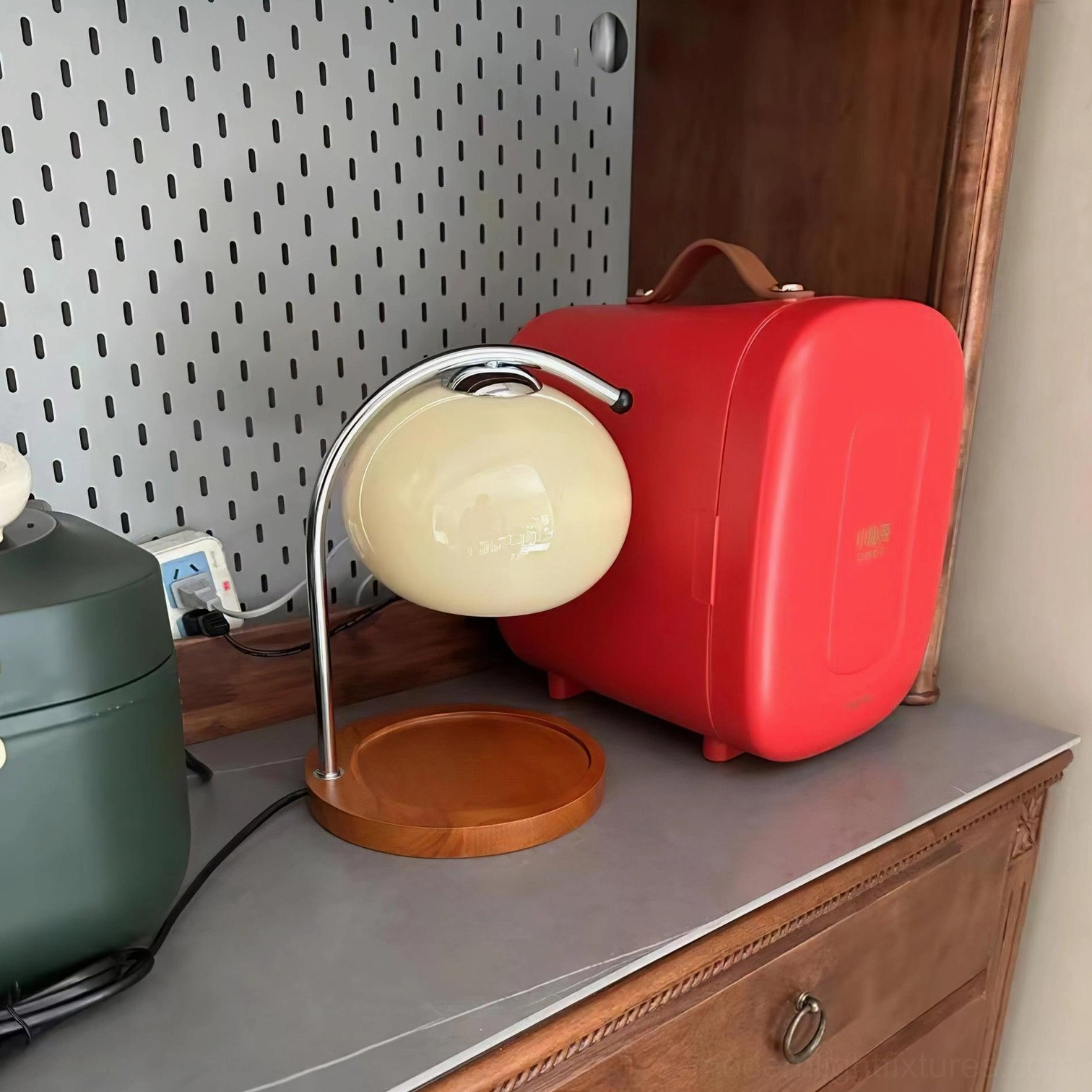 Mauri candle warmer lamp with cream white spherical shade and compact wooden base on dresser with pegboard wall