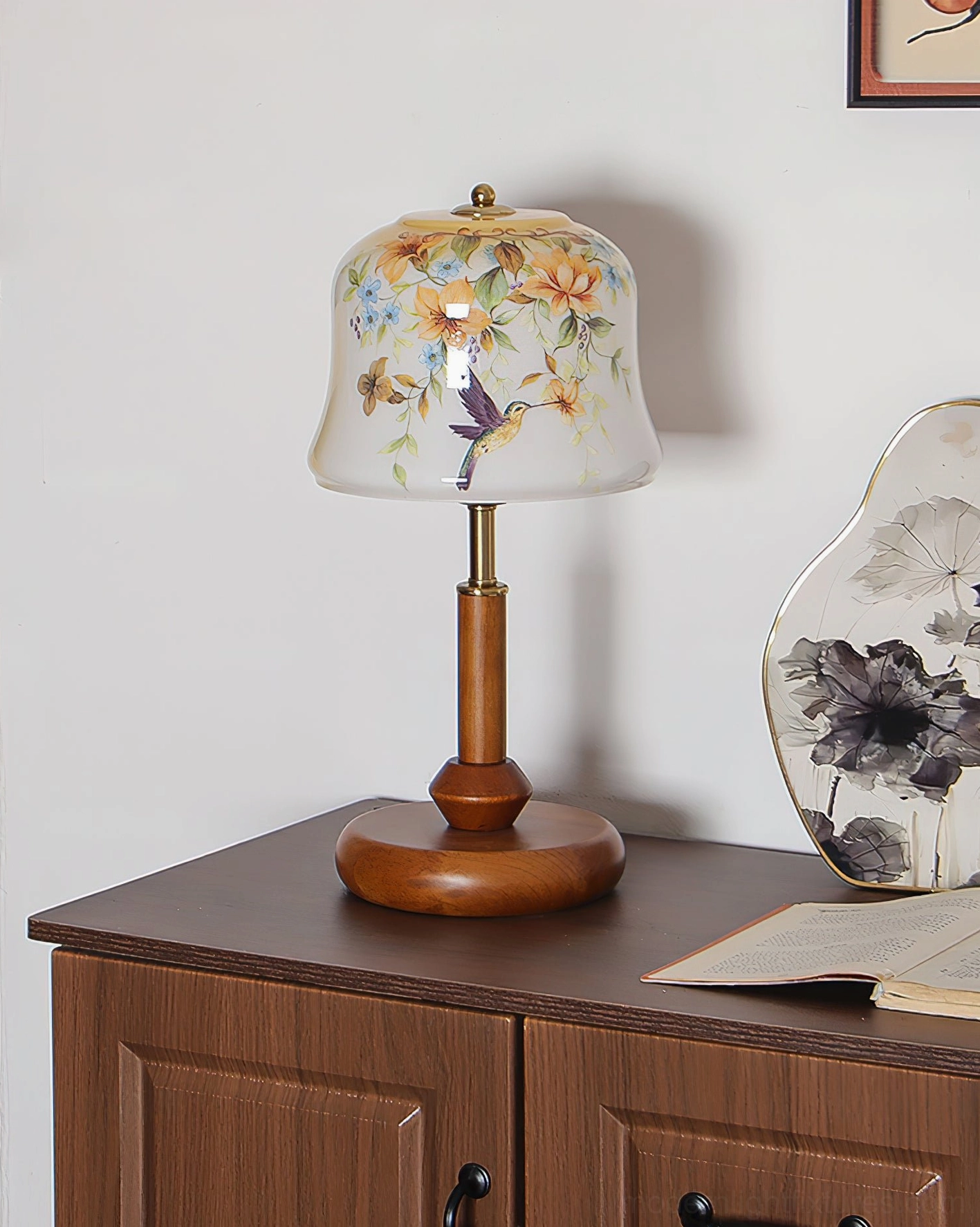 Meadow hand-painted table lamp displayed on wooden cabinet showing detailed floral hummingbird glass shade design