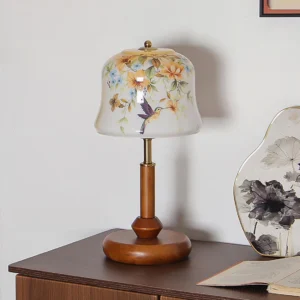 Meadow table lamp displaying floral and hummingbird hand-painted design on wooden dresser with decorative accessories
