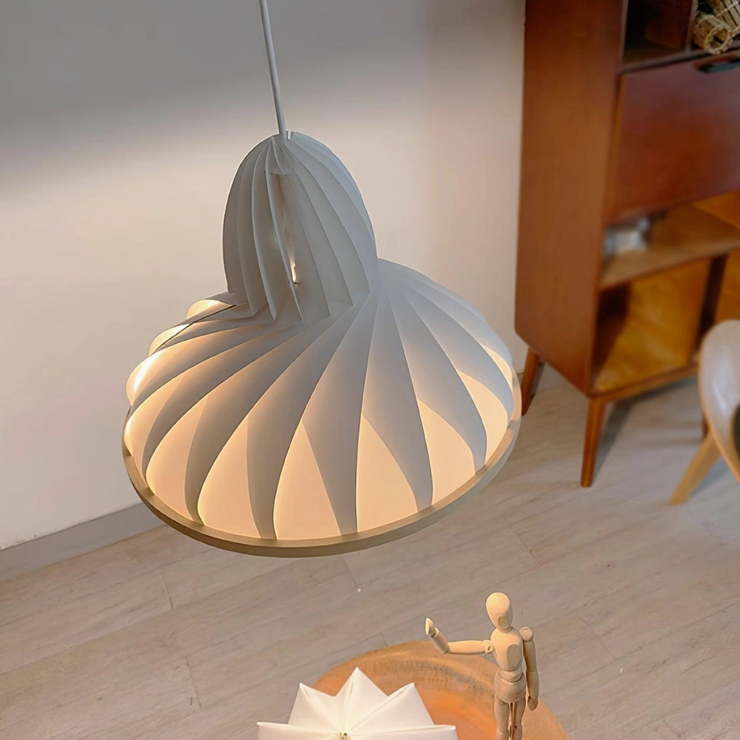 Meblo wave pendant light in home living corner with three-quarter side profile, warm ambient lighting matching wooden furniture tones