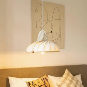 Modern Meblo pendant light hanging in living room corner with warm ambient lighting and abstract wall art, side profile showing ribbed texture