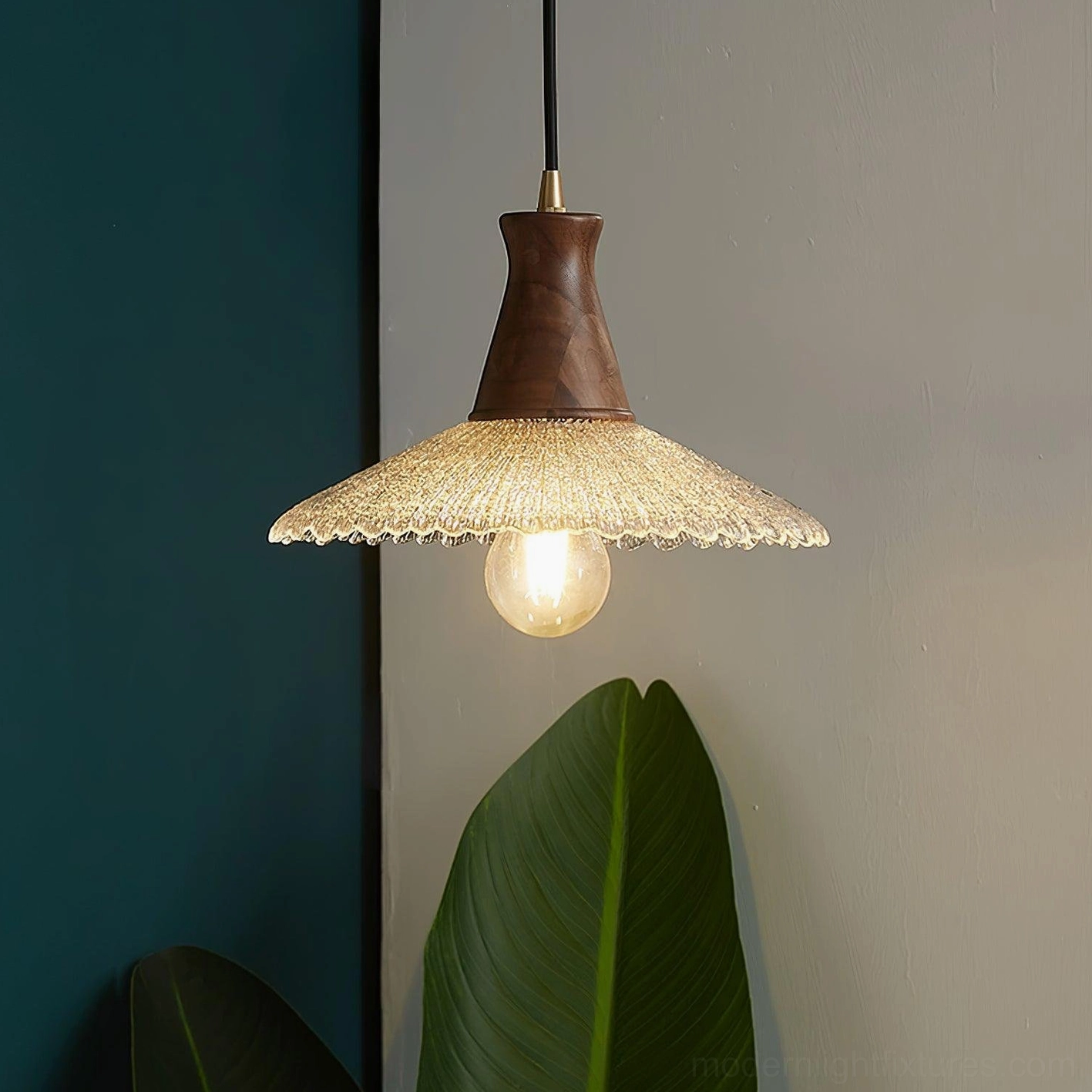 Medium diameter walnut pendant lamp with warm filament bulb in residential dining setting, three-quarter angle