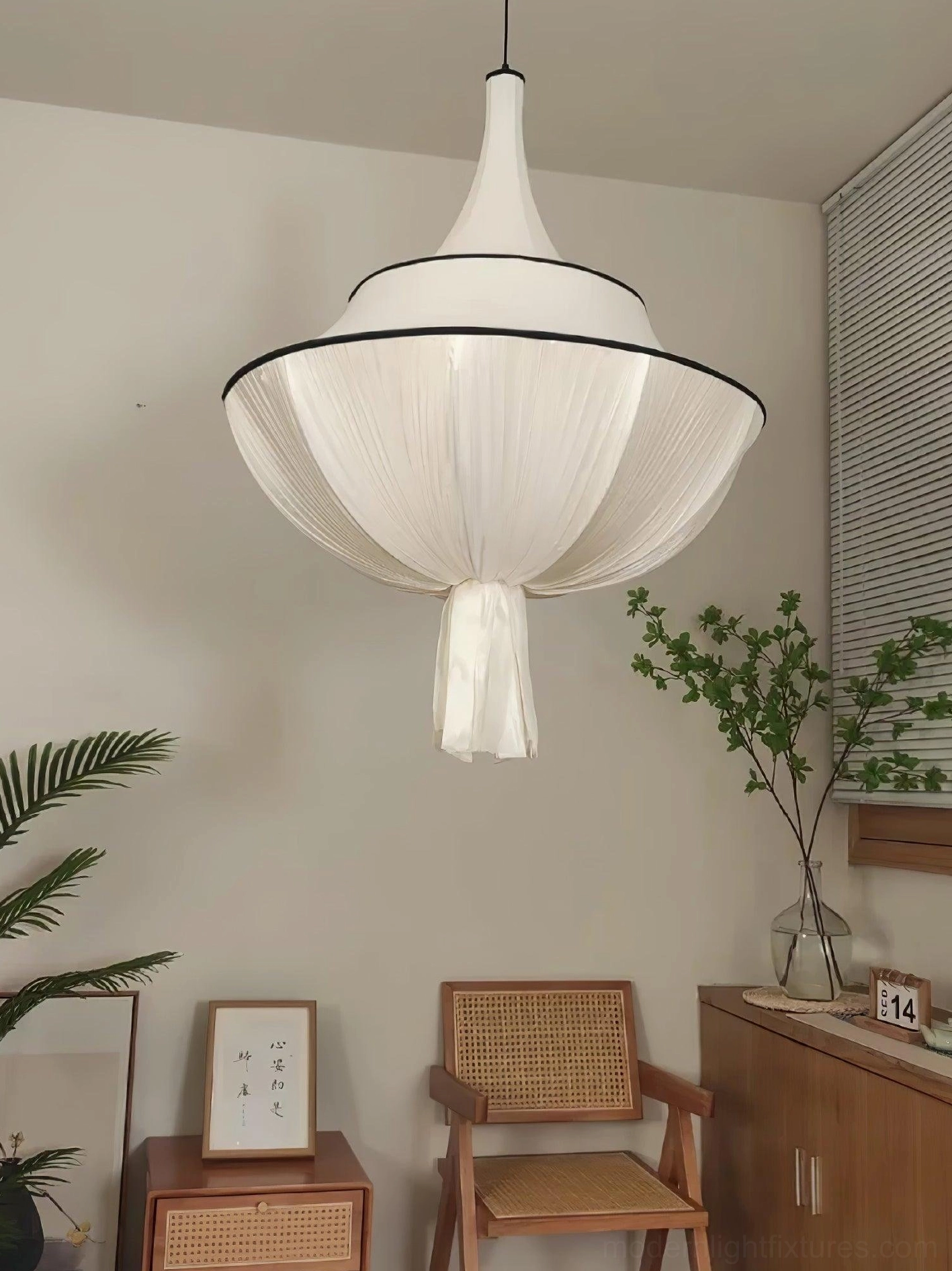 Meduse pleated fabric pendant light over dining table in minimalist room with wooden furniture and plants