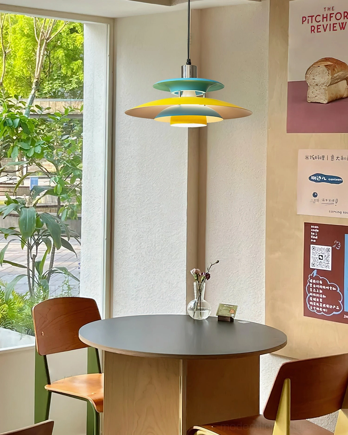 Mellowe mid-century pendant light with natural daylight above round wooden table in dining nook with outdoor-facing window