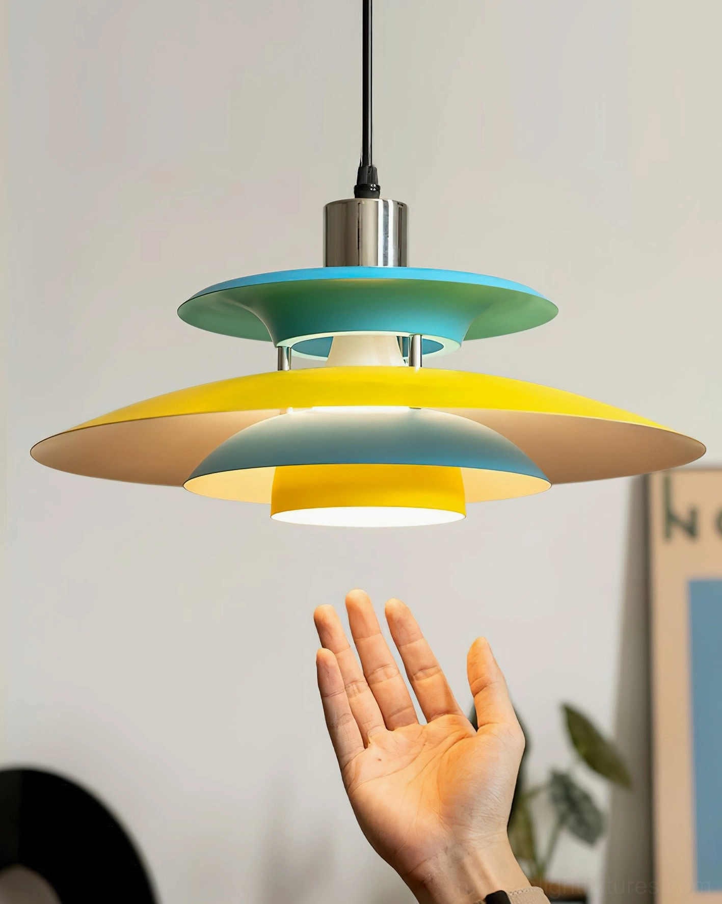 Mellowe colorblock pendant lamp with hand for scale showing warm ambient light emission and chrome hardware details