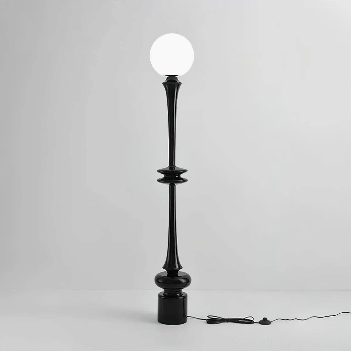 Black floor lamp with frosted glass orb and extended black power cord on white background