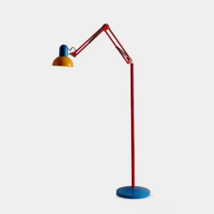 Memphis design floor lamp with cobalt blue base, cherry red adjustable arm, and yellow fabric shade - primary color blocked retro modern studio view