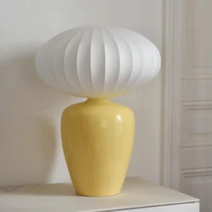 Yellow Meringue table lamp displayed in modern home interior cabinet corner with white ribbed shade and glossy ceramic base